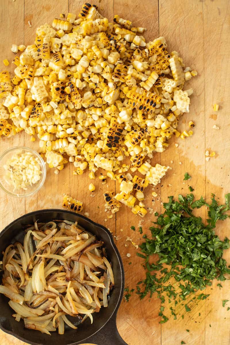 Prepped street corn ingredients on a cutting board.