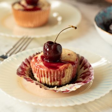 A peanut butter cheesecake with the cherry juice running down the side.