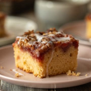 A slice of strawberry buttermilk coffee cake with pecan streusel on a small pink plate.